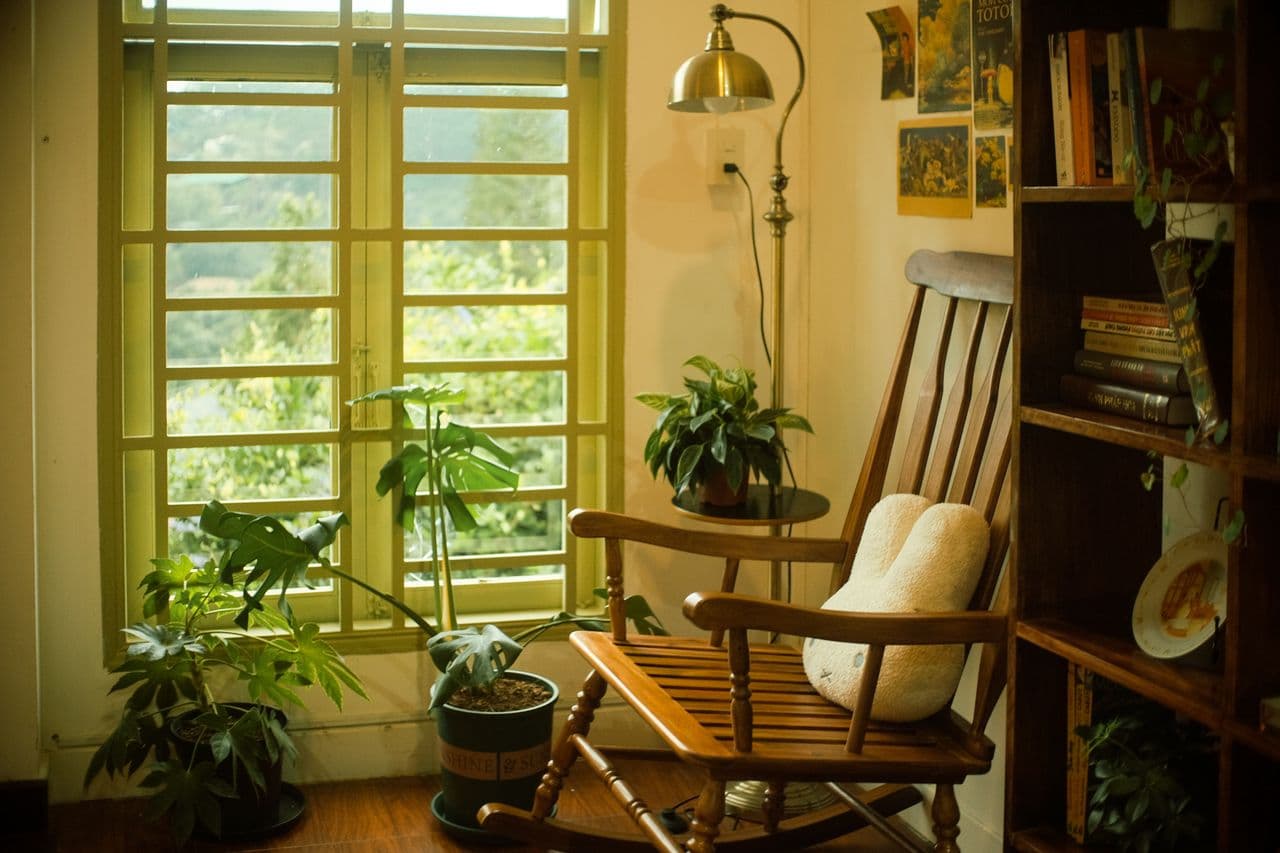 A cozy rocking chair in front of a window with plants